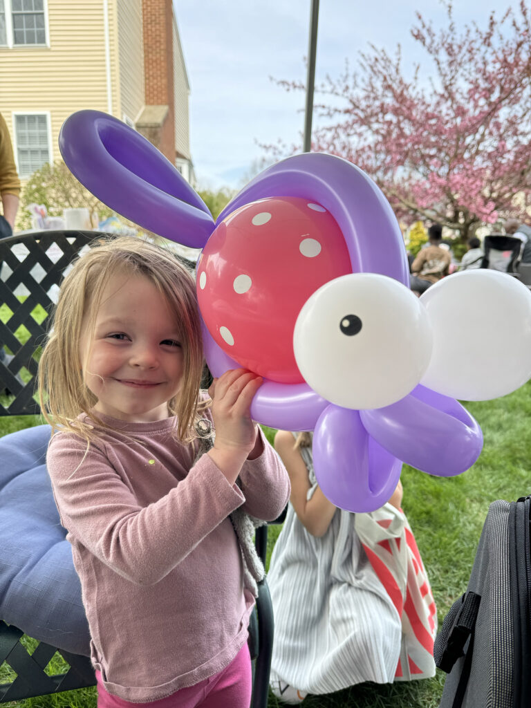 A child smiling at a backyard birthday in RI holding a large fish balloon animal