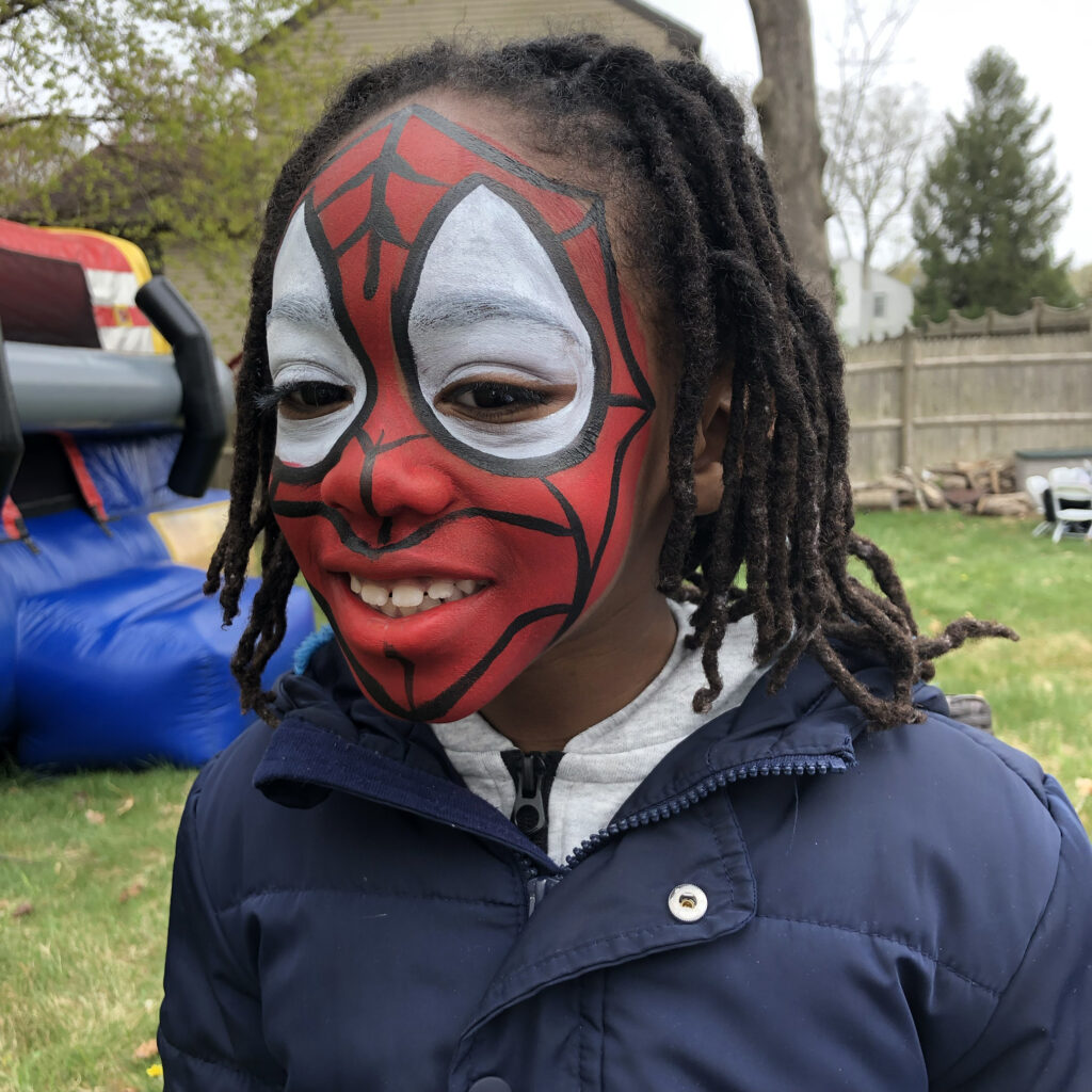 Face painting RI artist applies fun super hero designs for kids at a back yard birthday aprty