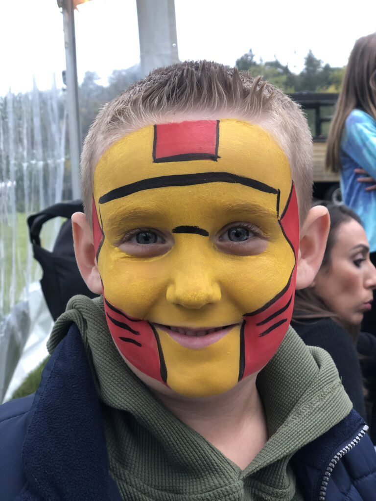 Face painting RI artist designs a super hero mask for child at a school fundraiser