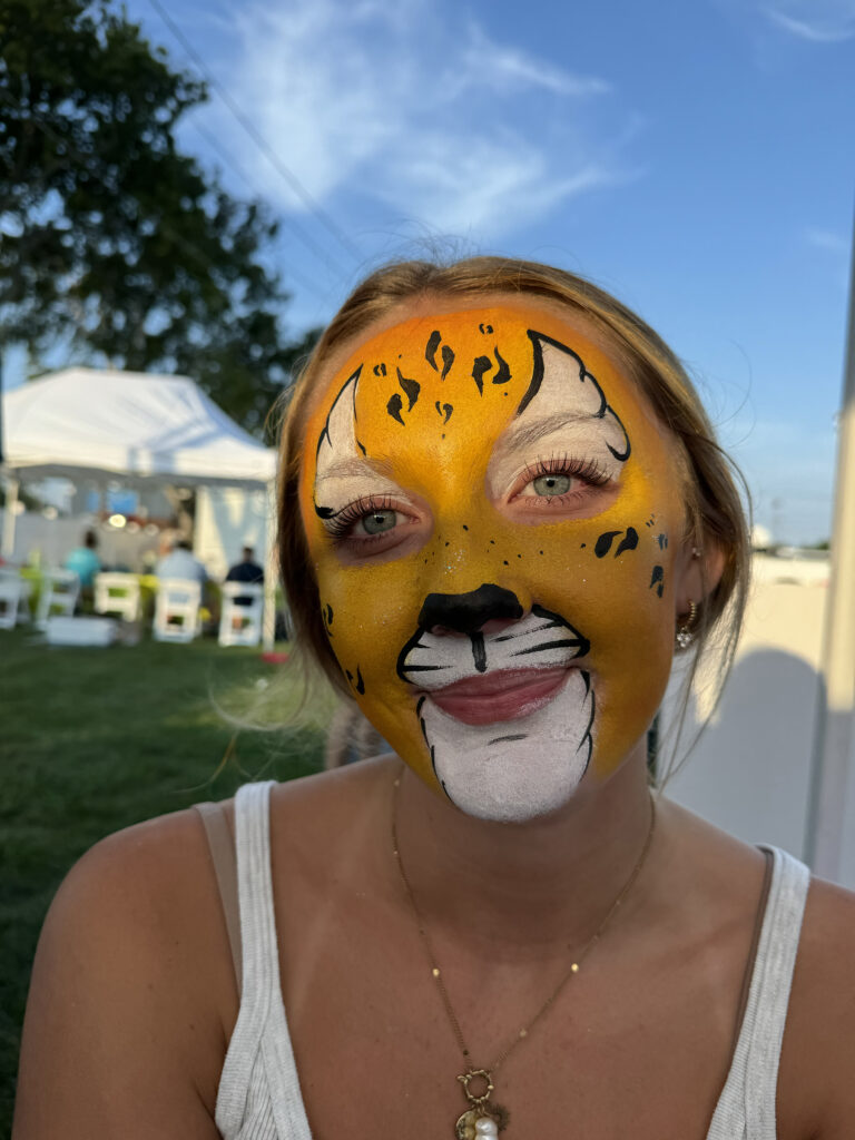 A tween with a cheetah face painting design outdoors in RI