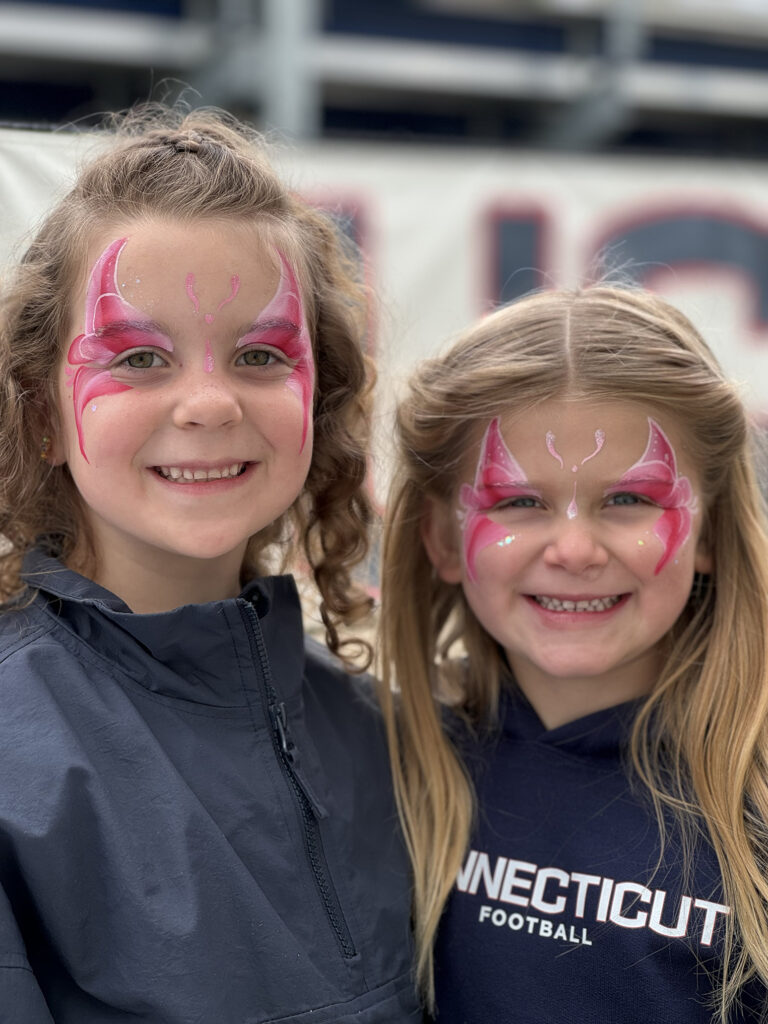 2 smiling girls with butterfly face paintings by face painter RI at a family gathering.