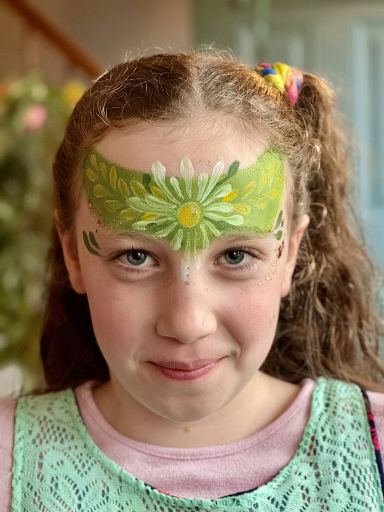 Face painting RI artist brings joy to kids with creative flower designs at a school event