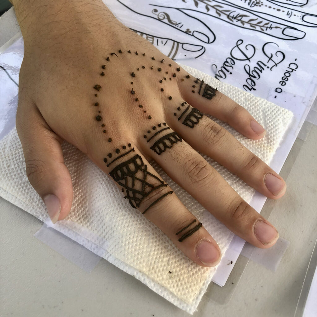 Henna artists Rhode Island design a minimalist design on a hand, shown on a white table