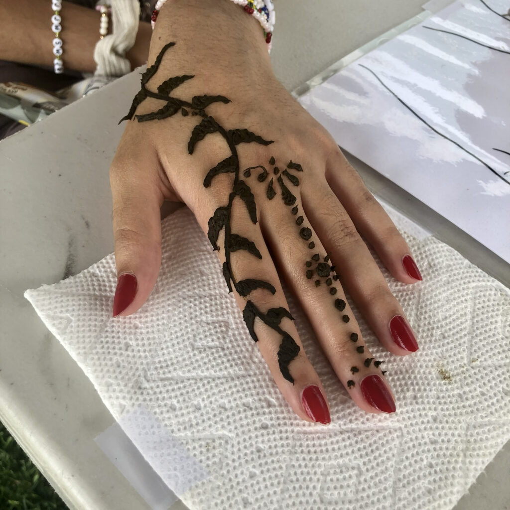 Elegant and modern henna hand design by henna artist Rhode Island, set on a white table