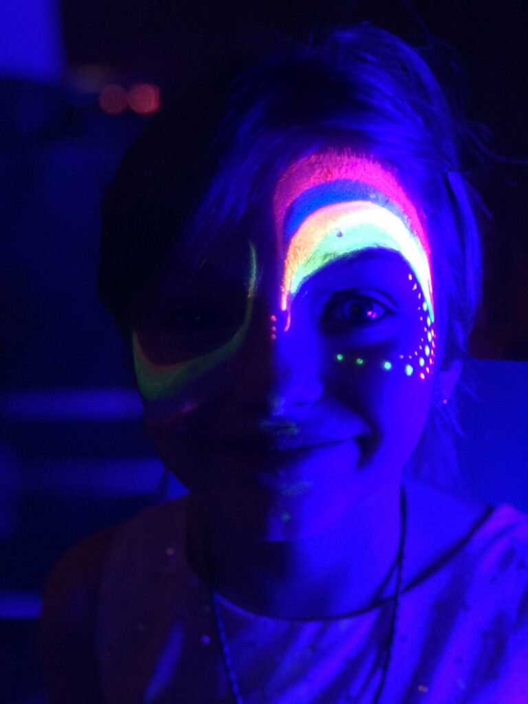 A small child with a rainbow face paint on